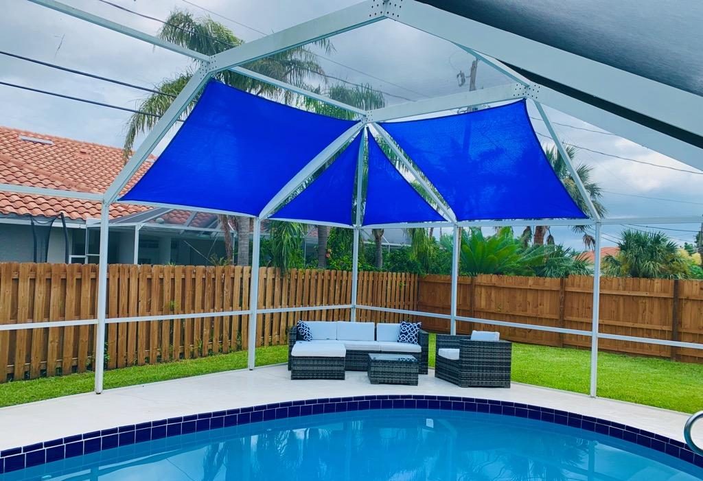 Shade sails over a pool cage seating area